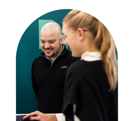 Tv&aring; leende Voky-anst&auml;llda som tittar ner p&aring; en dator